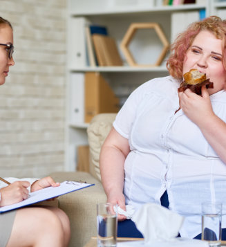 A woman enjoys a doughnut while seated comfortably on a couch